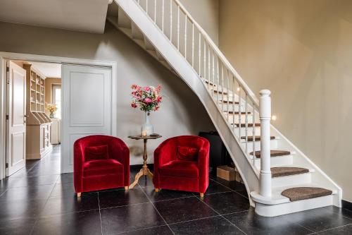 two red chairs and a table with a vase of flowers at B&B La Cereza in Oudenaarde