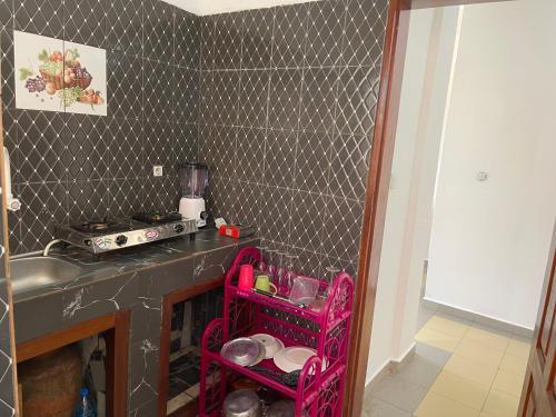 una cucina con fornelli e un carrello rosa al suo interno di Sweetpiol a Yaoundé