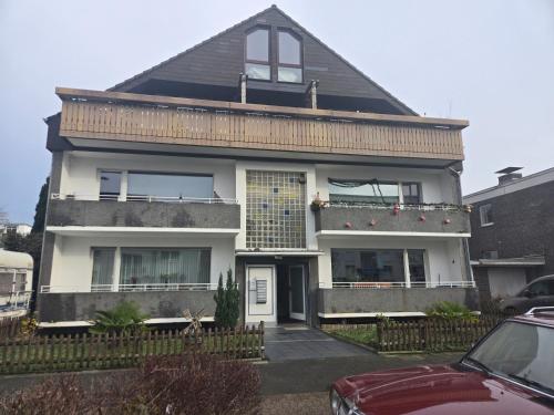 a white house with a red car parked in front of it at Messeapartment nahe Düsseldorf in Meerbusch