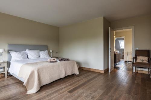 a bedroom with a large bed and a chair at B&B La Cereza in Oudenaarde