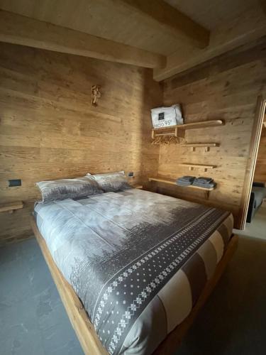 a large bed in a room with wooden walls at Sabbionaccio Apartments & Spa in Chiesa in Valmalenco