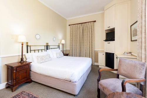 a hotel room with a bed and a chair at Queen's Hotel by BON Hotels in Oudtshoorn