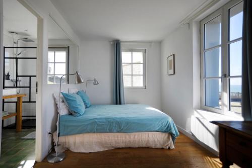 a bedroom with a bed with blue sheets and windows at Brise du Large - Maison d'Ault in Ault