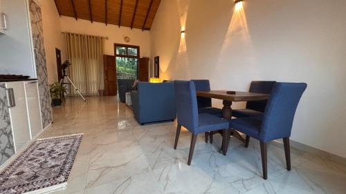 a dining room with a table and blue chairs at Chathu Holiday Home in Kandy