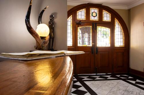 a room with a door and a table with antlers on it at Queen's Hotel by BON Hotels in Oudtshoorn