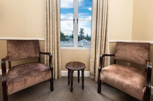 two chairs and a table in front of a window at Queen's Hotel by BON Hotels in Oudtshoorn