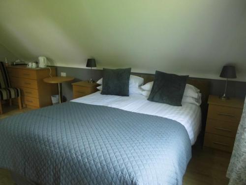 a bedroom with a bed with a blue blanket and pillows at Eas Dun Lodge in Donegal