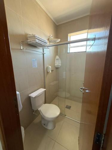 a bathroom with a toilet and a glass shower at Hotel Village Campinas in Campinas