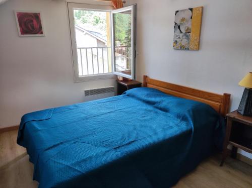une chambre avec un lit bleu avec une fenêtre dans l'établissement APPARTEMENT Ax Les Thermes, à Ax-les-Thermes