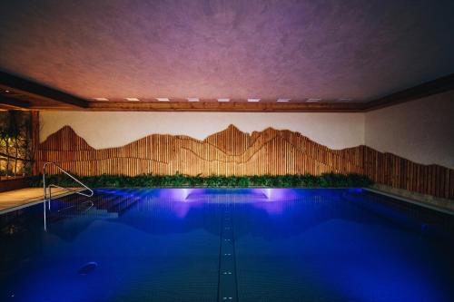 a swimming pool in a house with a wooden wall at Wellness Penzion Zora Family in Tatranská Lomnica