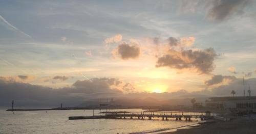 un coucher de soleil sur une étendue d'eau avec une jetée dans l'établissement Le QG - CANNES - Palais du Festival, à Cannes