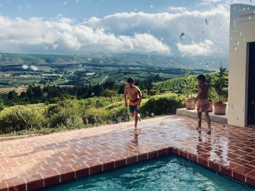 two men standing on the edge of a swimming pool at Spioenkop Wines Farm House in Elgin