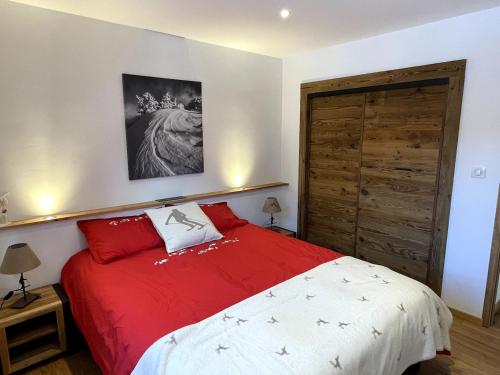 - une chambre avec un lit rouge et blanc et une porte en bois dans l'établissement Very nice apartment, slopeside, à Saint-Chaffrey