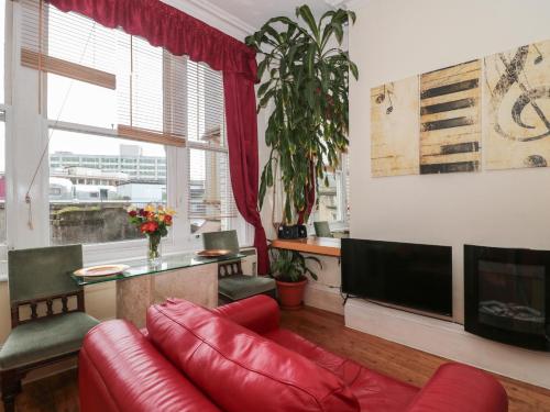 a living room with a red couch and a television at 9 Old City Chambers in Bristol