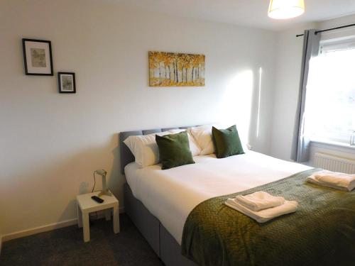 イースト・キルブライドにある4 Bedroom Newly Refurbished Home in East Kilbrideの緑の枕が付いた大きなベッドのある寝室