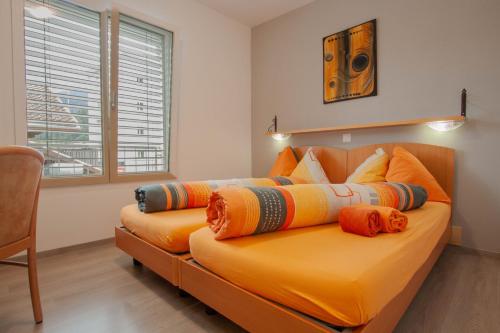 a large orange bed with pillows on it in a room at Ristorante Pensione Chalet Stazione in Poschiavo
