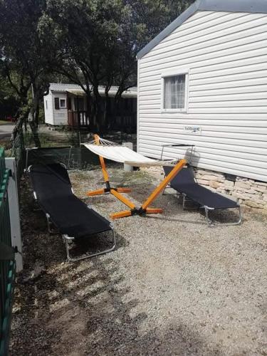 two chairs and a boat sitting next to a building at Mobil Home CAMPING MUNICIPAL ORGNAC LAVEN in Orgnac-lʼAven