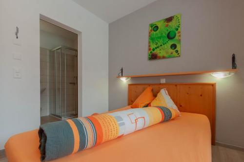 a bedroom with a bed with an orange bedspread at Ristorante Pensione Chalet Stazione in Poschiavo