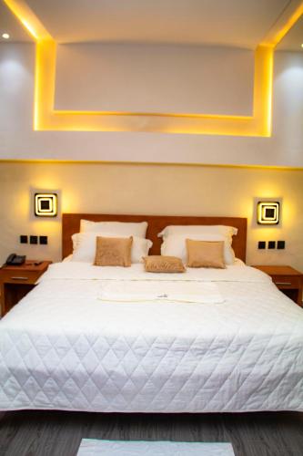 ein Schlafzimmer mit einem großen weißen Bett mit zwei Kissen in der Unterkunft Hôtel L'apéro in Cotonou