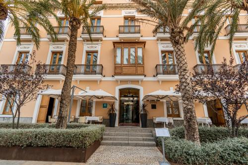 a building with palm trees in front of it at Mirador de Dalt Vila-Relais & Chateaux in Ibiza Town