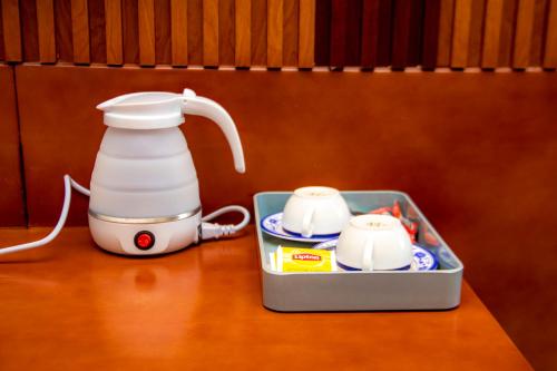 a tea kettle and two cups on a table at Hôtel L'apéro in Cotonou