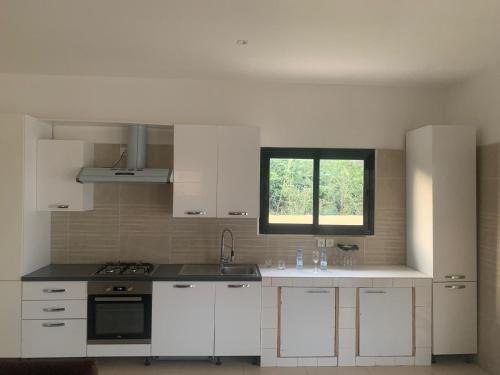 a kitchen with white cabinets and a window at Résidence Kanissa in Cap Skirring