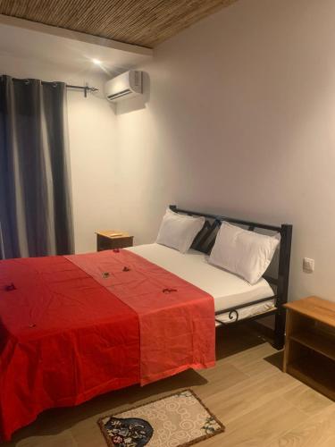 a bedroom with a bed with a red blanket at Résidence Kanissa in Cap Skirring
