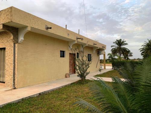 a yellow building with a tree in front of it at Résidence Kanissa in Cap Skirring