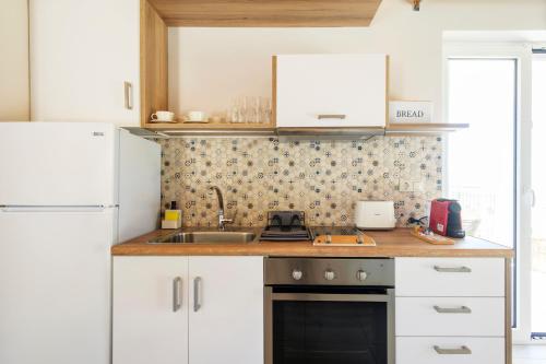 a kitchen with white cabinets and a sink at ALMA HILLS Gialova in Gialova