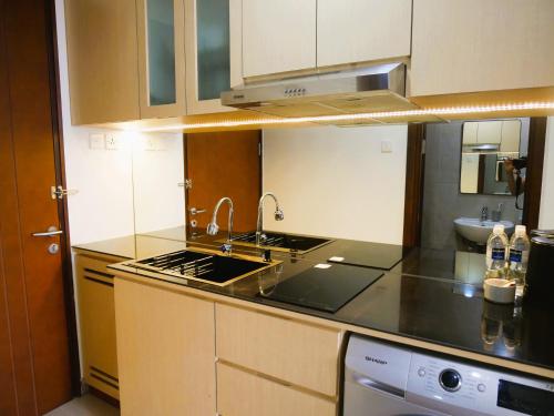 a kitchen with a sink and a stove top oven at Meisterstadt Pollux Habibie in Batam Center