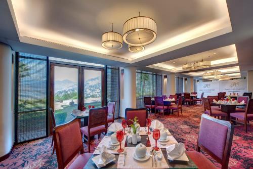 a dining room with tables and chairs and windows at Pearl Continental Hotel, Muzaffarabad in Muzaffarabad