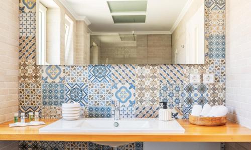 a bathroom with a sink and blue and white tiles at ALMA HILLS Gialova in Gialova