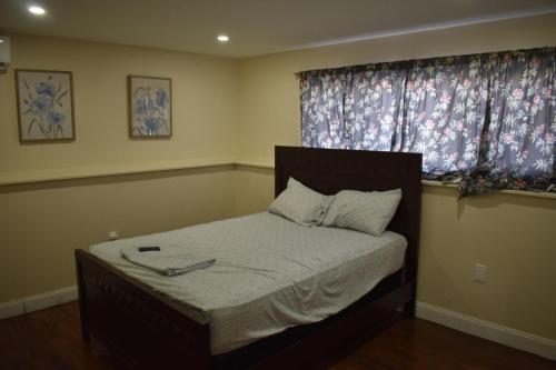 a bedroom with a bed with a window with curtains at West Babylon Bliss in West Babylon