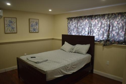 a bedroom with a bed with a window with curtains at West Babylon Bliss in West Babylon