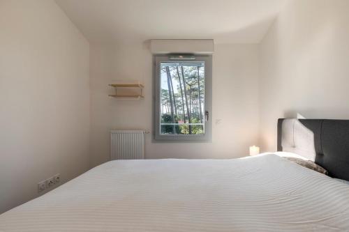 une chambre avec un lit blanc et une fenêtre dans l'établissement Seignosse- Terraced Villa -Ocean-Family, à Seignosse