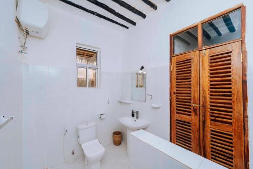 a white bathroom with a toilet and a sink at Bwejuu Beach Duplex Bungalow in Bwejuu