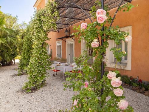 a garden with pink roses growing around a building at Les chambres d'hôtes du Domaine de Roque Haute in Portiragnes