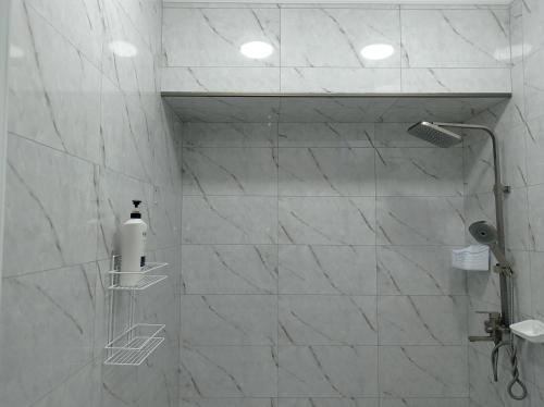 Un baño con ducha con paredes de mármol blanco. en Тихий Замок, en Bishkek