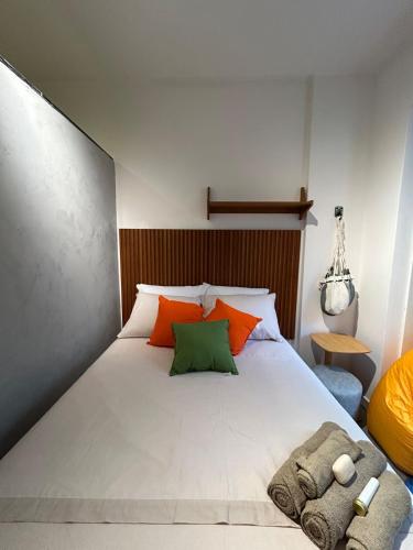 a bedroom with a large white bed with orange and green pillows at Studio Moderno in Botafogo in Rio de Janeiro