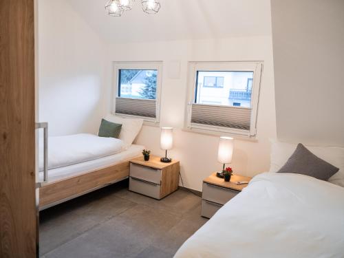 ein Schlafzimmer mit zwei Betten und zwei Fenstern in der Unterkunft Ferienhaus Waldzauber-Winterberg in Winterberg