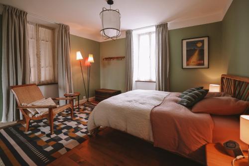 a bedroom with a bed and a chair and a window at Les Chambres de Lasserre - Chambres et Table d'hôtes in Lasserre