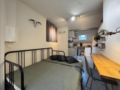 une petite chambre avec un lit et une cuisine dans l'établissement Charmant studio en centre ville de Fontainebleau, à Fontainebleau