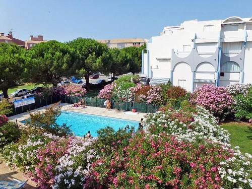 - une piscine fleurie devant un bâtiment dans l'établissement AS25454 -P3 + Cabine en duplex dans résidence avec piscines, au Grau-du-Roi