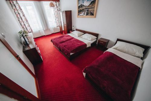 a room with two beds and a red carpet at Wellness Penzion Zora Family in Tatranská Lomnica