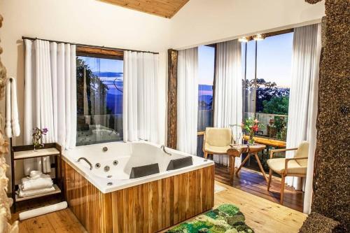 a large bathroom with a bath tub and a table at Suítes Ad`vinho in Lavras Novas