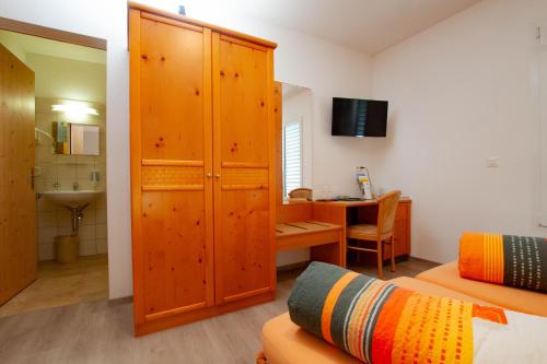 a bedroom with a large wooden cabinet and a desk at Ristorante Pensione Chalet Stazione in Poschiavo