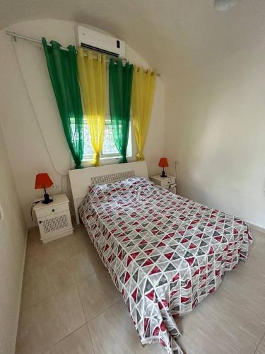 a bedroom with a bed with green and yellow curtains at Dar El Bhar, villa sul mare in Kelibia