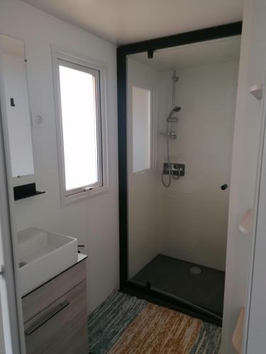 La salle de bains est pourvue d'une fenêtre, d'un lavabo et d'un miroir. dans l'établissement MOBIl HOME LE NARBONNAIS, à Valras-Plage