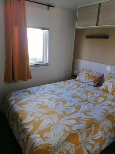 un grand lit dans une chambre avec une fenêtre dans l'établissement MOBIl HOME LE NARBONNAIS, à Valras-Plage