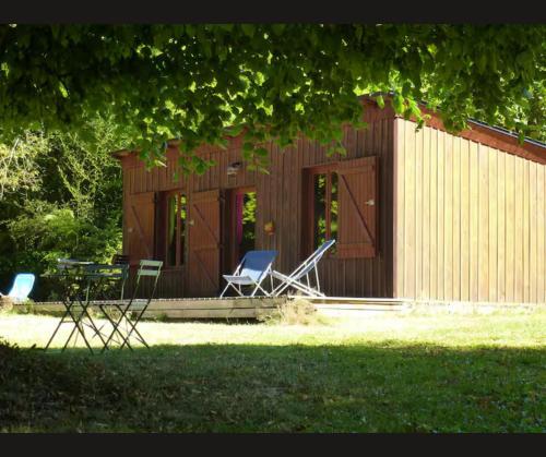 two chairs and a table in front of a building at Cabane Limousine au bord d'un étang in Bonnac-la-Côte